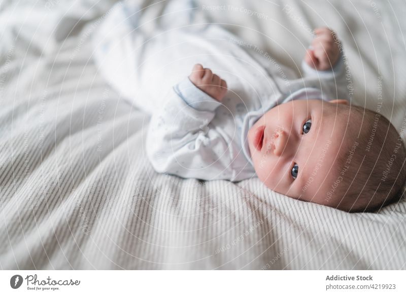 Cute newborn baby resting on crumpled bed innocent curious attentive sweet gentle portrait home harmony infant cloth idyllic focus gaze babyhood bedroom creased
