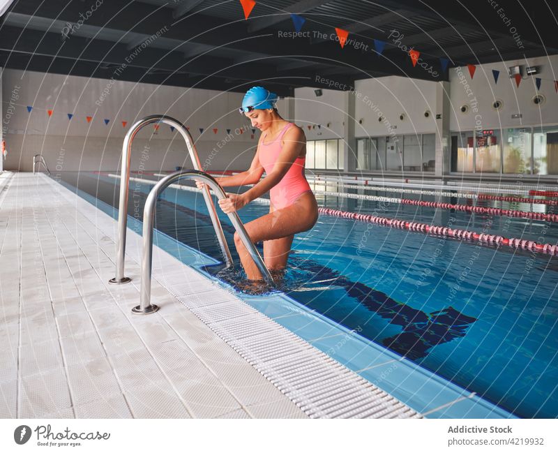 Swimmer in swimming pool with lanes before workout swimmer sport wellness vitality training fit woman goggles swimwear body handrail sportswoman feminine alone