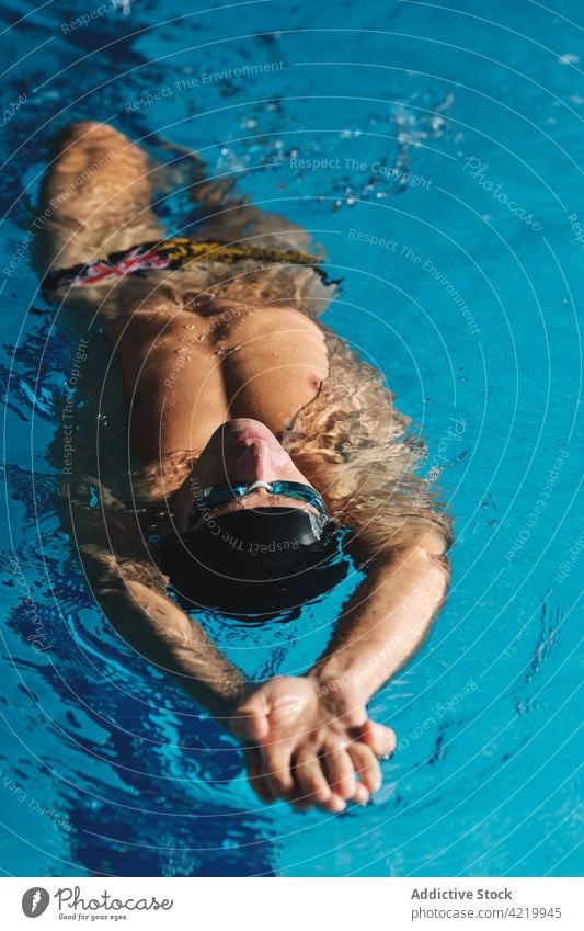 Sportsman in goggles swimming in pool during workout swimmer sport arms raised training exercise practice motivation energy strength masculine wellness fit