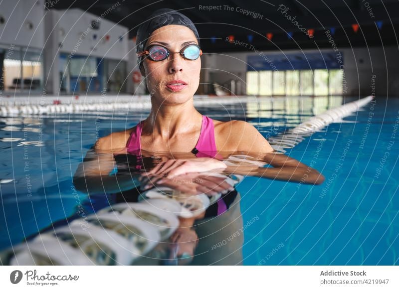 Swimmer in swimsuit in pool during break from workout swimmer sport training wellness contemplate woman portrait professional lane line floating marker dreamy