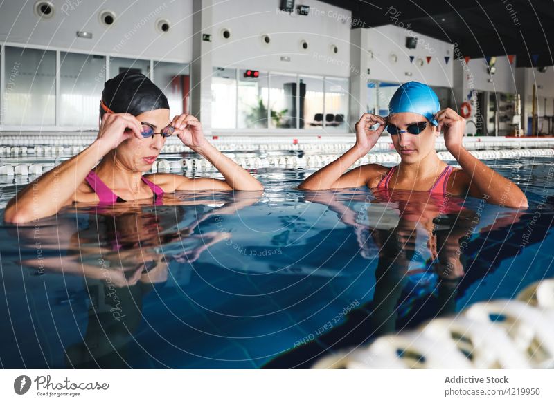 Swimmers putting on goggles before training in pool swimmer put on sport workout wellbeing professional women water swimming cap together serious practice