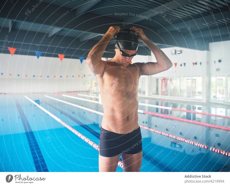 Fit swimmer in goggles against pool before working out sportsman swimming prepare abdomen workout body masculine swimming trunks athlete hand behind head