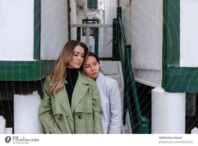 Loving couple of women standing on beach near building autumn lesbian homosexual together relationship season coat cloudy house love girlfriend shore lgbt close