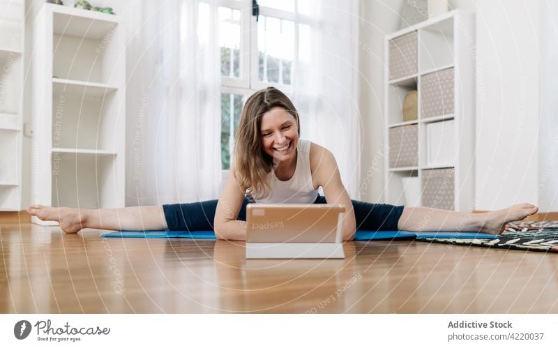 Cheerful woman sitting in Wide Splits pose and doing yoga split practice video online tutorial lesson home flexible female asana wide splits pose