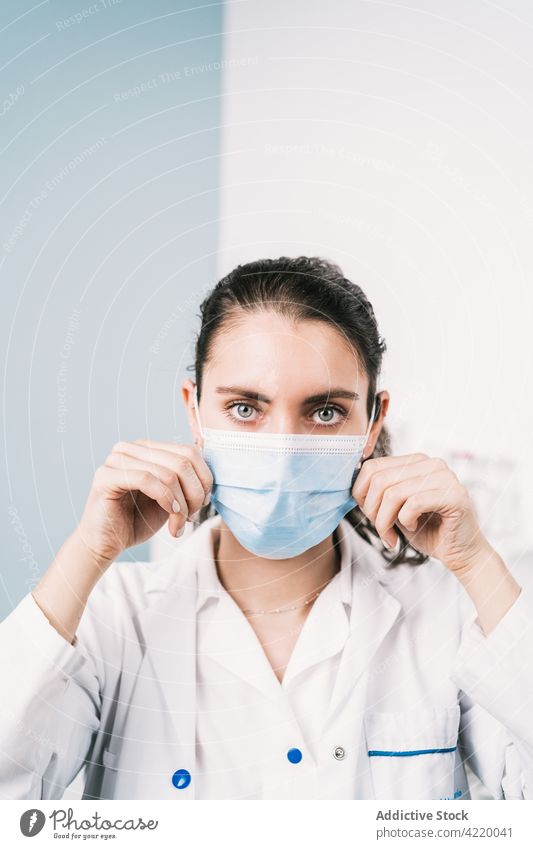 Nurse putting on disposable mask in clinic nurse put on protect health care medical woman portrait show respiratory confident uniform profession hospital work