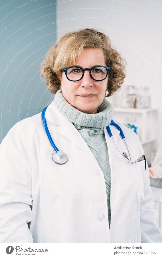 Mature physician with stethoscope at work in clinic confident uniform profession specialist eyeglasses woman hospital portrait professional doctor gaze