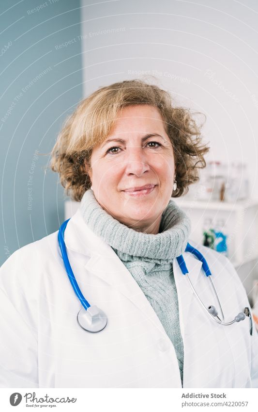 Mature physician with stethoscope at work in clinic confident uniform profession specialist woman hospital portrait professional doctor gaze self assured