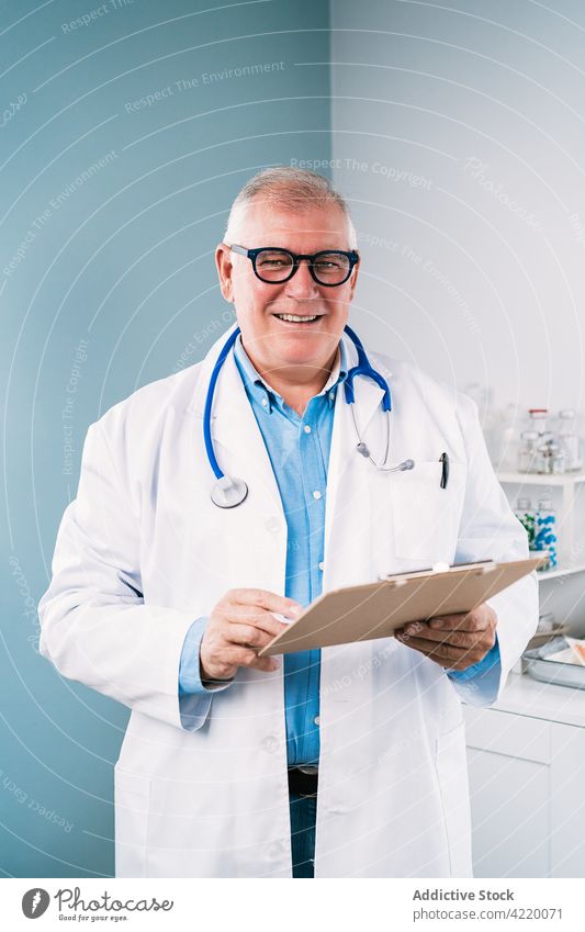 Physician reading on paper in clinic physician uniform smile work profession happy specialist medical man robe cheerful stethoscope instrument doctor write