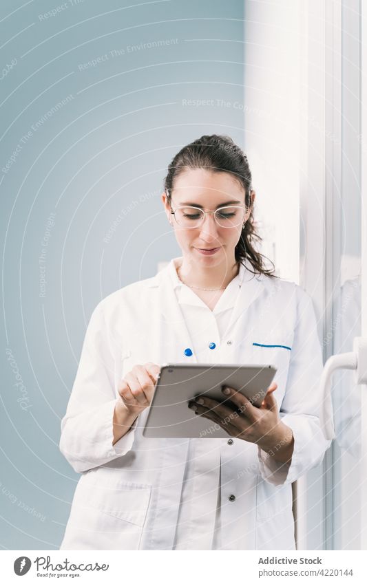 Nurse in uniform working on tablet in hospital nurse professional internet online woman reflection clinic using gadget device doctor eyeglasses accessory