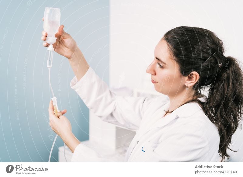 Nurse preparing medical dropper in clinic nurse drop counter prepare professional bottle liquid work woman substance transparent plastic material wire attentive