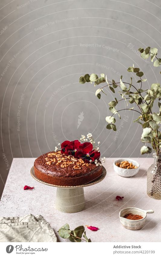 Sweet cake with nuts and flowers on stand on table chocolate biscuit baked dessert sweet pastry serve delicious gourmet food tasty fresh cuisine homemade treat
