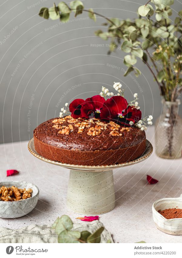 Sweet cake with nuts and flowers on stand on table chocolate biscuit baked dessert sweet pastry serve delicious gourmet food tasty fresh cuisine homemade treat