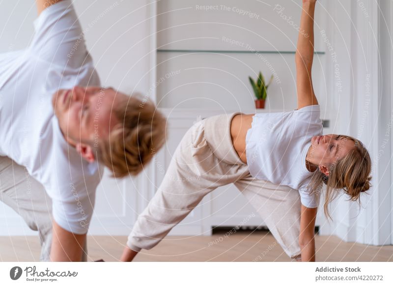 Couple practicing yoga in triangle pose together at home couple morning practice stretch namaste asana relax relationship trikonasana activewear wellbeing