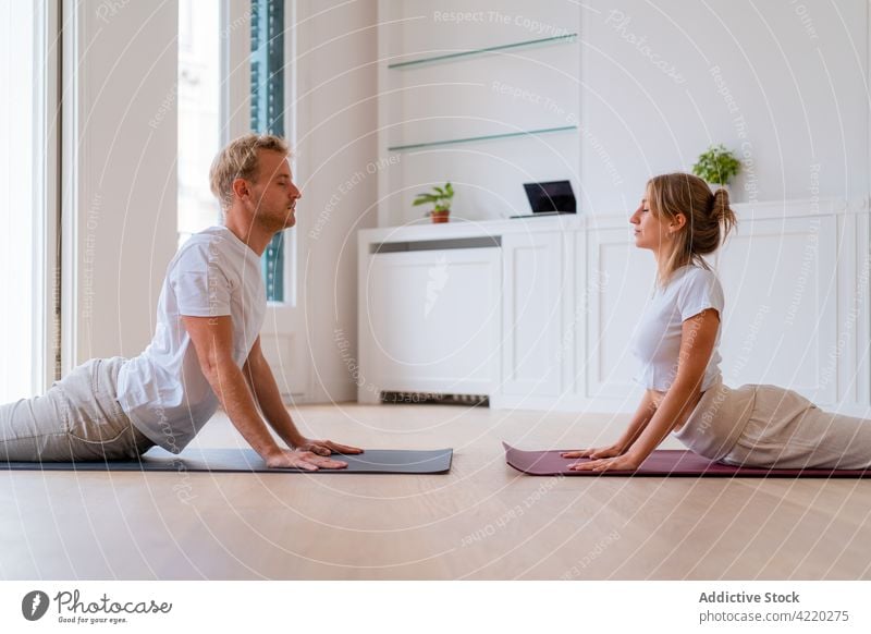 Couple doing yoga in Cobra pose at home couple morning together practice cobra pose flexible harmony calm tranquil wellness balance stretch peaceful healthy
