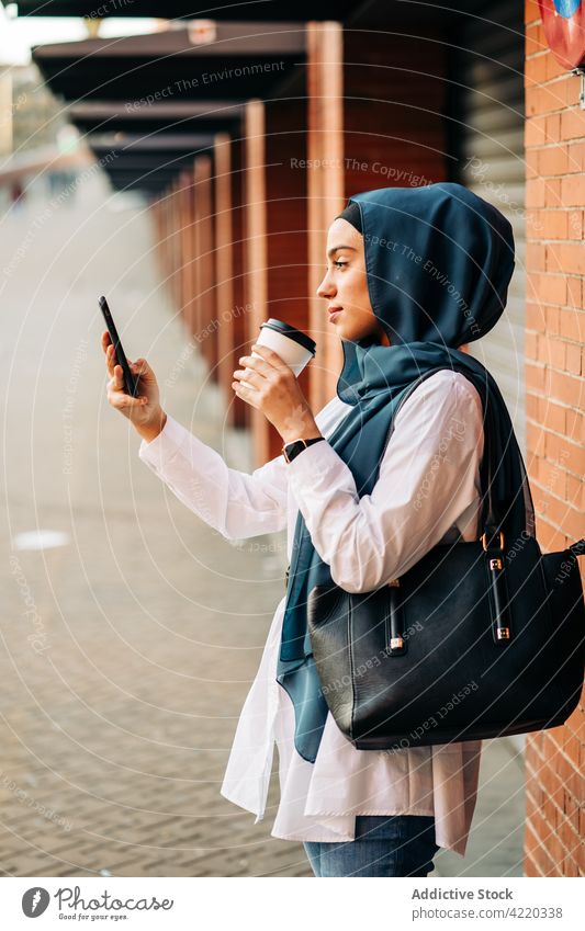 Muslim woman taking self shot on smartphone on train station selfie railway station hijab wait self portrait takeaway drink female ethnic muslim cellphone