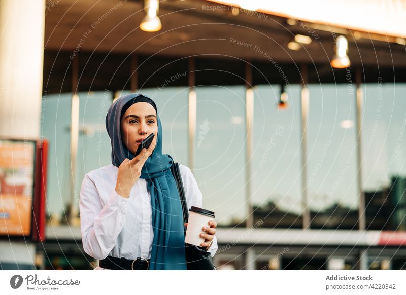 Muslim woman recording audio message on smartphone voice social media talk mobile ethnic muslim headscarf street gadget communicate using device hijab tradition