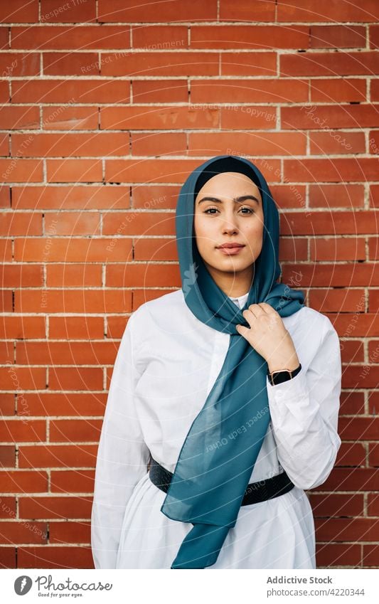 Ethnic woman in hijab in city leaning on brick wall street female ethnic muslim headscarf headwear style headdress urban stand culture headgear daytime outbreak