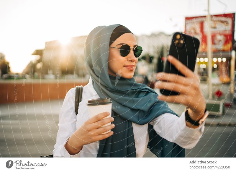 Muslim woman taking selfie on smartphone social media mobile female ethnic muslim headscarf street gadget communicate using device hijab tradition trendy