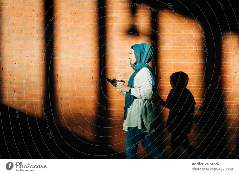 Muslim woman using smartphone in train station browsing underground takeaway city drink surfing hijab female ethnic muslim mobile internet gadget headscarf