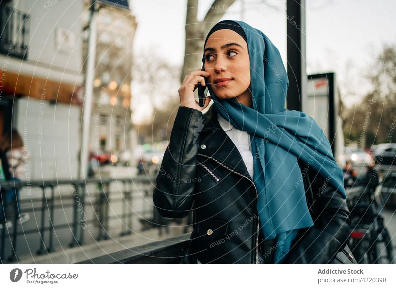 Ethnic woman in hijab using smartphone in street city talking tradition headscarf internet female ethnic muslim gadget mobile online connection charming urban