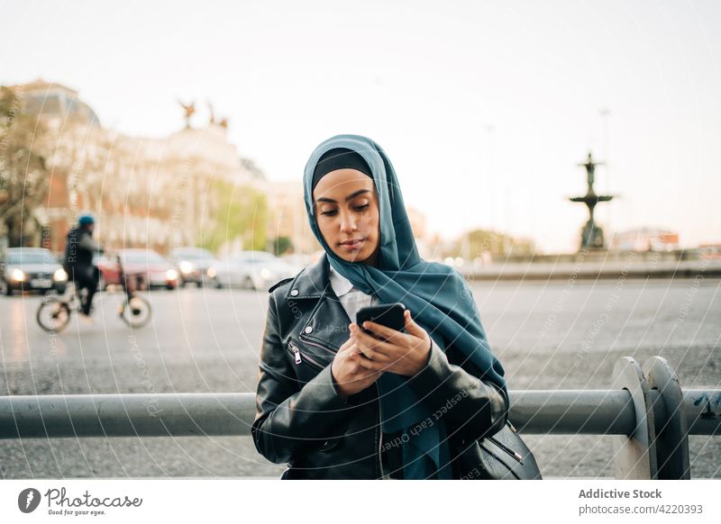 Ethnic woman in hijab using smartphone in street city browsing tradition headscarf internet female ethnic muslim gadget mobile online connection surfing message
