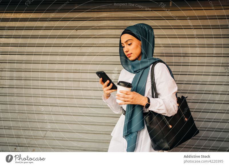 Muslim woman browsing smartphone near closed shop hijab wait takeaway drink female ethnic muslim cellphone mobile using internet gadget device station