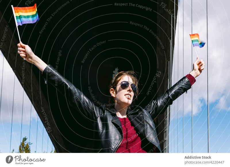 Carefree woman with LBGT flags in street lgbt lesbian rainbow lgbtq proud homosexual freedom pride female city arms raised liberty gay urban right bridge