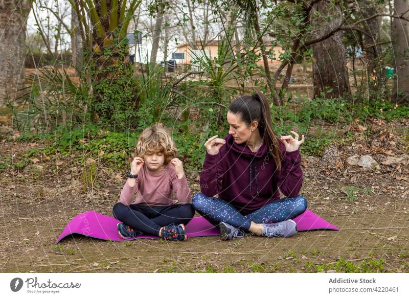 Mother with son meditating on yoga mat in park mom meditate healthy lifestyle mudra vitality stress relief legs crossed woman lotus pose padmasana together boy