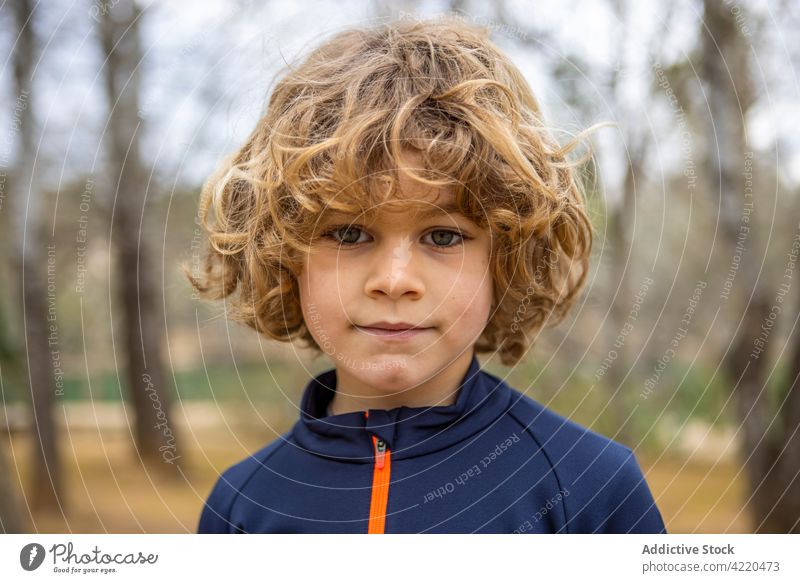 Boy in sportswear with wavy hair in daytime boy charming friendly childhood sincere wistful casual style alone portrait hoodie gray soft pensive solitary kid