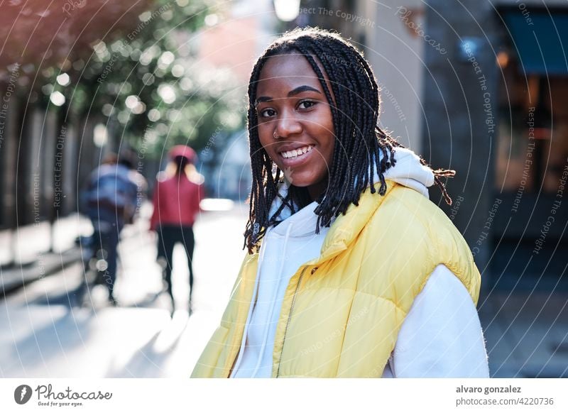 Young woman smiling while standing outdoors. che african american urban street black style city closeup braids hairstyle clothing afro smile one confident