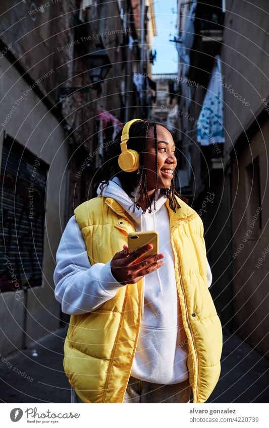 Woman listening music with headphones and phone. woman che mobile urban device enjoying technology outdoor african american wireless female outdoors smartphone