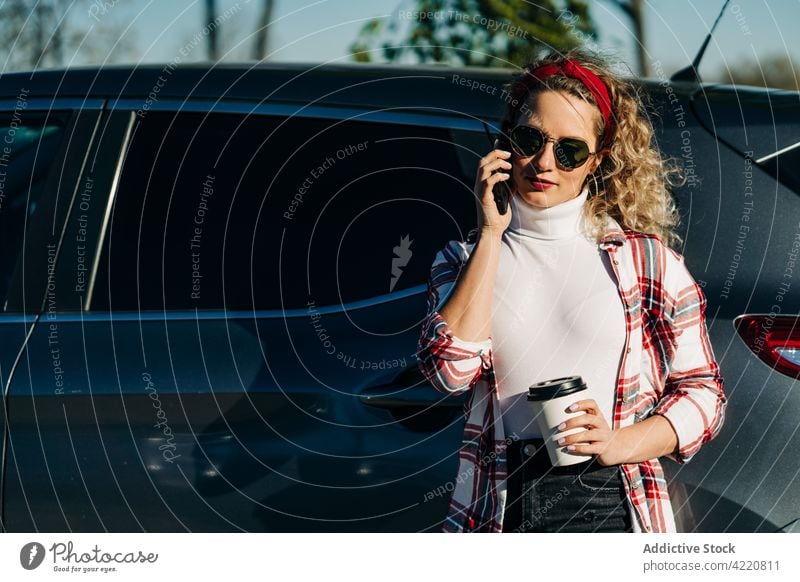 Stylish woman speaking on smartphone near car city talk takeaway drink automobile conversation female call gadget device phone call using modern style to go