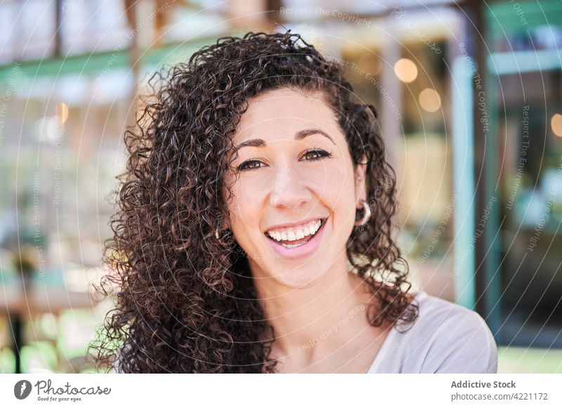 Happy ethnic woman with curly hair in restaurant toothy smile friendly sincere romantic charismatic charming pleasant portrait happy positive glad content