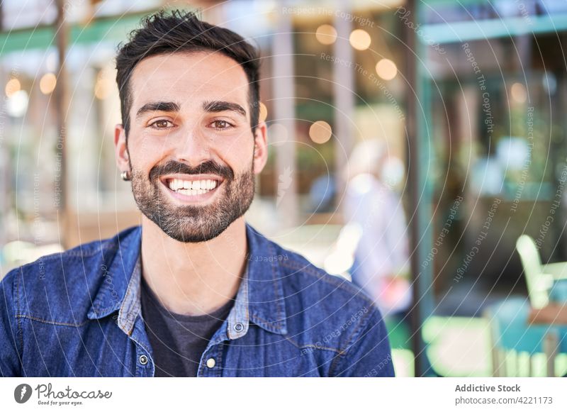 Smiling ethnic man with beard in restaurant cheerful kind candid masculine brutal macho virile portrait denim jacket casual style toothy smile friendly sincere