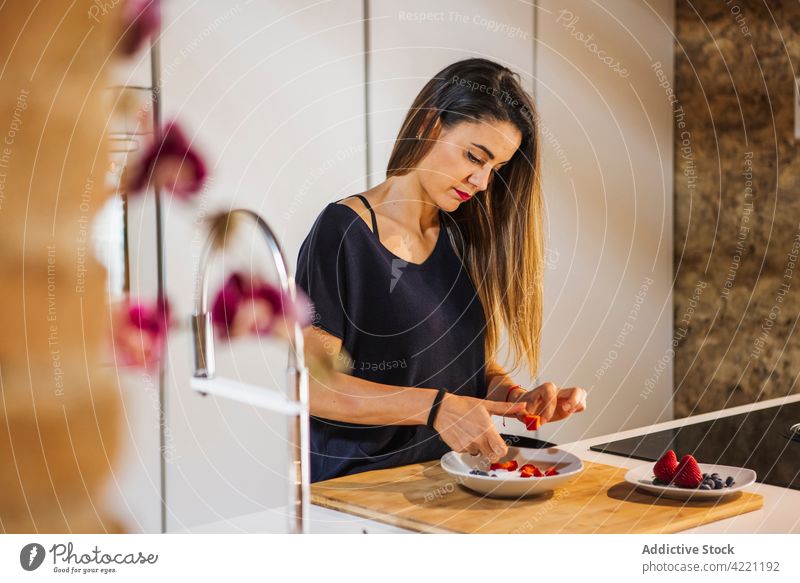 Concentrated woman cutting fresh strawberry for breakfast in kitchen culinary recipe vitamin healthy food delicious prepare natural concentrated home blueberry
