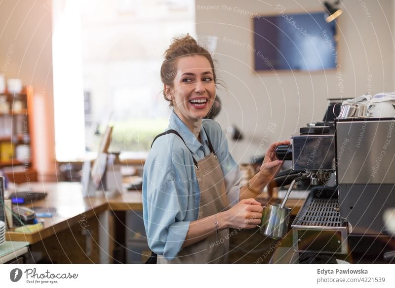 Female barista making coffee people woman young adult casual attractive female smiling happy indoors Caucasian toothy enjoying cafe restaurant apron business
