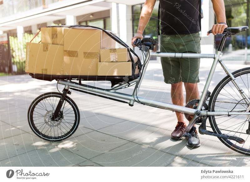 Bike courier making a delivery people young adult man male smiling happy blue collar Courier dispatch rider delivery man delivering package packages boxes