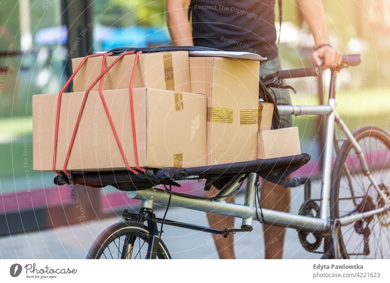 Bike courier making a delivery people young adult man male smiling happy blue collar Courier dispatch rider delivery man delivering package packages boxes
