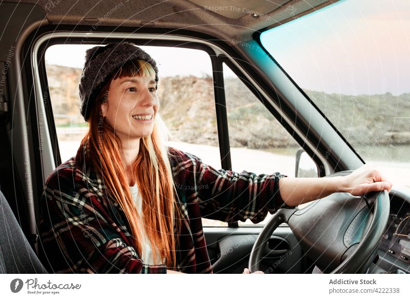 Cheerful woman sitting in van in mountains traveler truck hipster trip driver parked female vehicle transport smile freedom holiday cheerful vacation enjoy seat