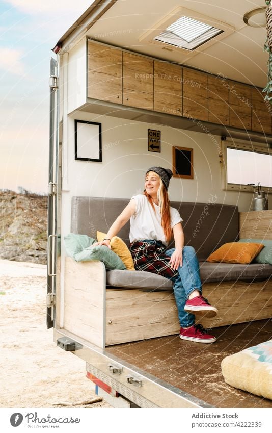 Content woman relaxing on sofa in van travel traveler truck lake hipster vacation enjoy female sit rest holiday summer trip style couch shore lakeside tourism