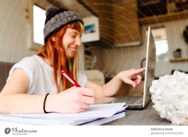 Traveling woman working remotely in van travel freelance telework smile truck take note female happy sit table laptop notebook write cheerful notepad memo glad