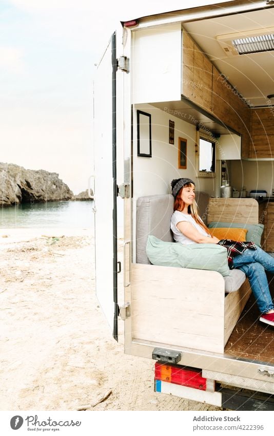 Content woman relaxing on sofa in van travel traveler truck lake hipster vacation enjoy female sit rest holiday summer trip style couch shore lakeside tourism