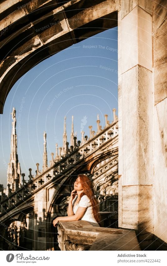 Anonymous tourist contemplating city from balcony of old cathedral traveler admire architecture decor aged woman town sunshine ornament religion historic