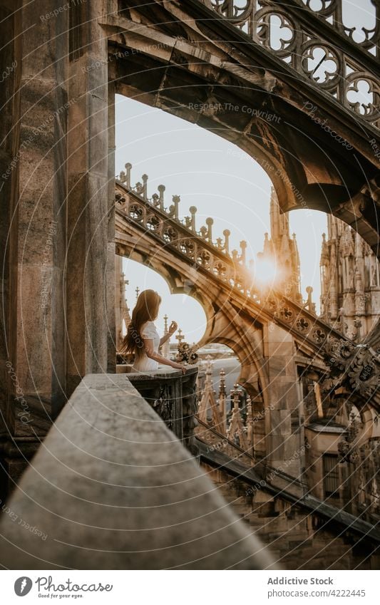 Anonymous tourist contemplating city from balcony of old cathedral traveler admire architecture decor aged woman town sunshine ornament religion historic