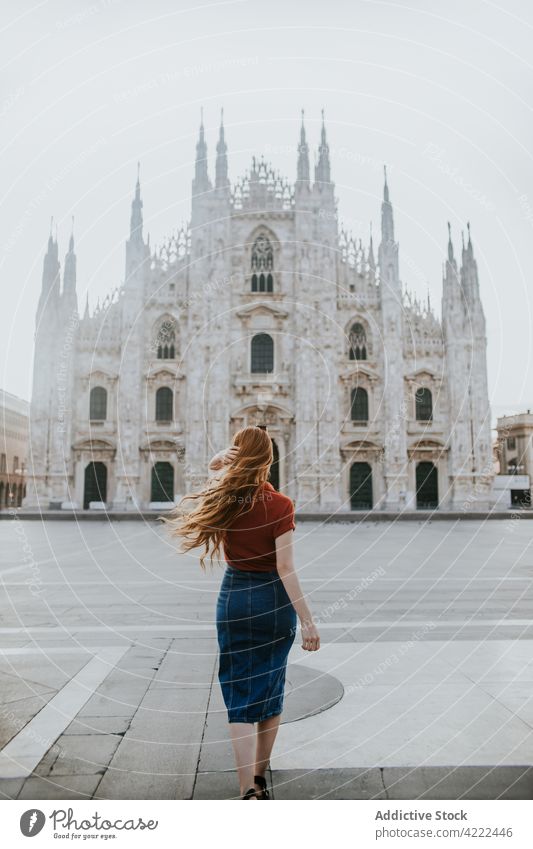 Unrecognizable traveler against Duomo facade in windy weather in town duomo cathedral architecture decor religion majestic woman urban flying hair admire city