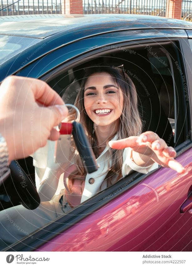 Happy buyer in new car receiving ignition key in town pass happy modern woman person cheerful charming feminine friendly city style automobile contemporary