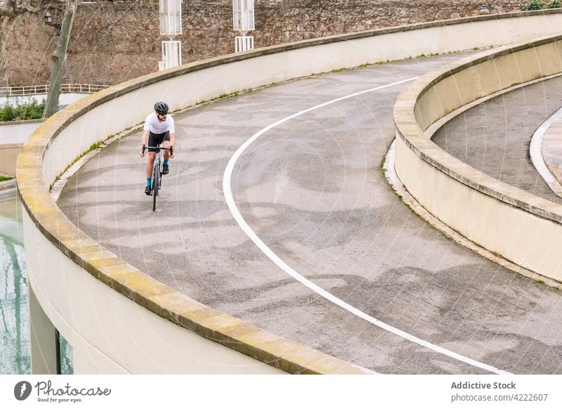 Cyclist riding bicycle on wavy road in town bicyclist ride bike sport cycling training workout practice man biker transport roadway asphalt curved vehicle