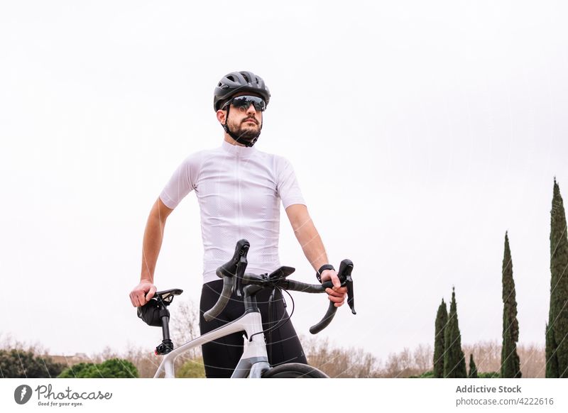 Bearded biker in sunglasses with bicycle under white sky cyclist sport masculine macho virile confident style man bicyclist professional transport vehicle