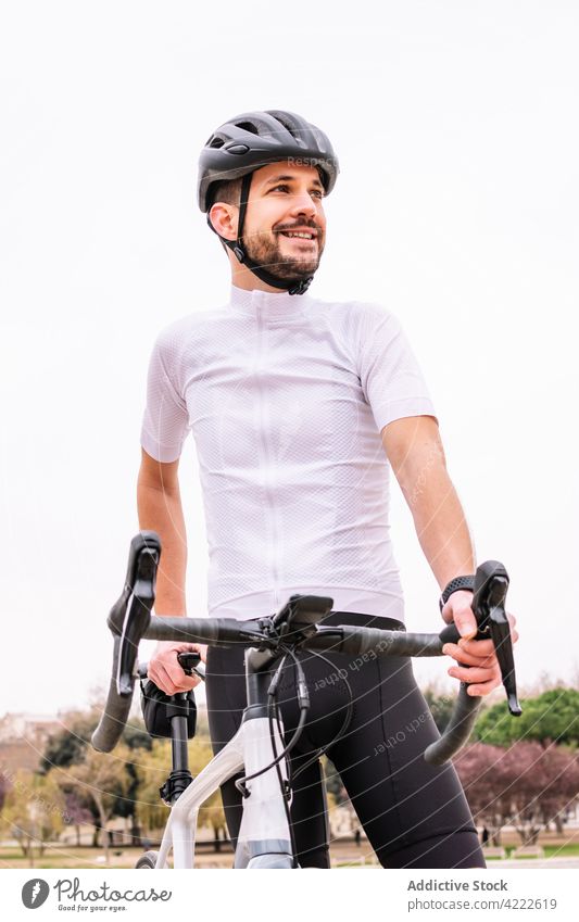 Bearded biker with bicycle under white sky cyclist sport masculine macho virile confident style man bicyclist professional transport vehicle helmet modern