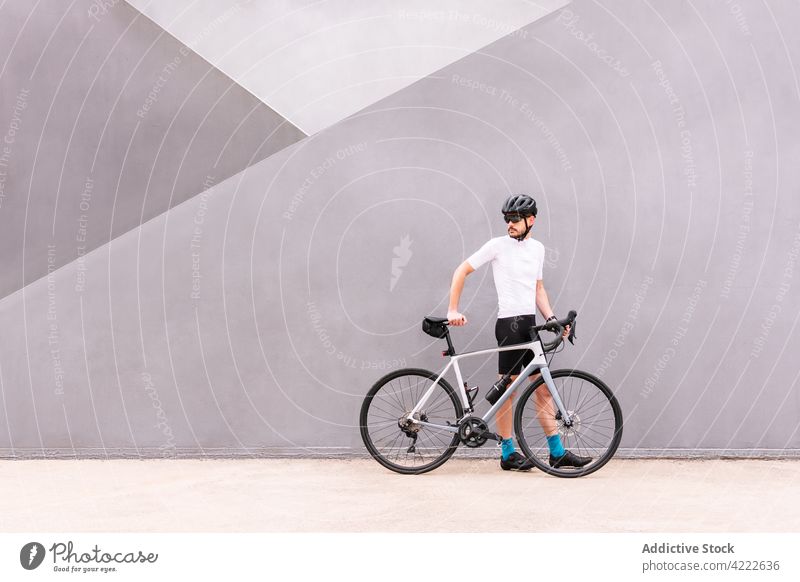 Cyclist with bicycle walking on urban pavement bicyclist bike sport professional style masculine man transport vehicle sock helmet sunglasses modern macho town